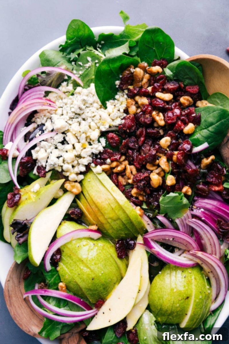 A beautifully presented pear salad on a white plate, ready to be served and enjoyed, with a fork gently placed beside it.