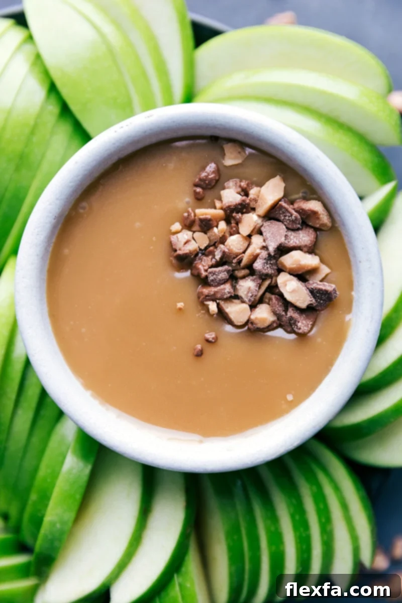 A bowl of golden caramel sauce, generously topped with crunchy chopped Heath bars, ready to be served and savored.