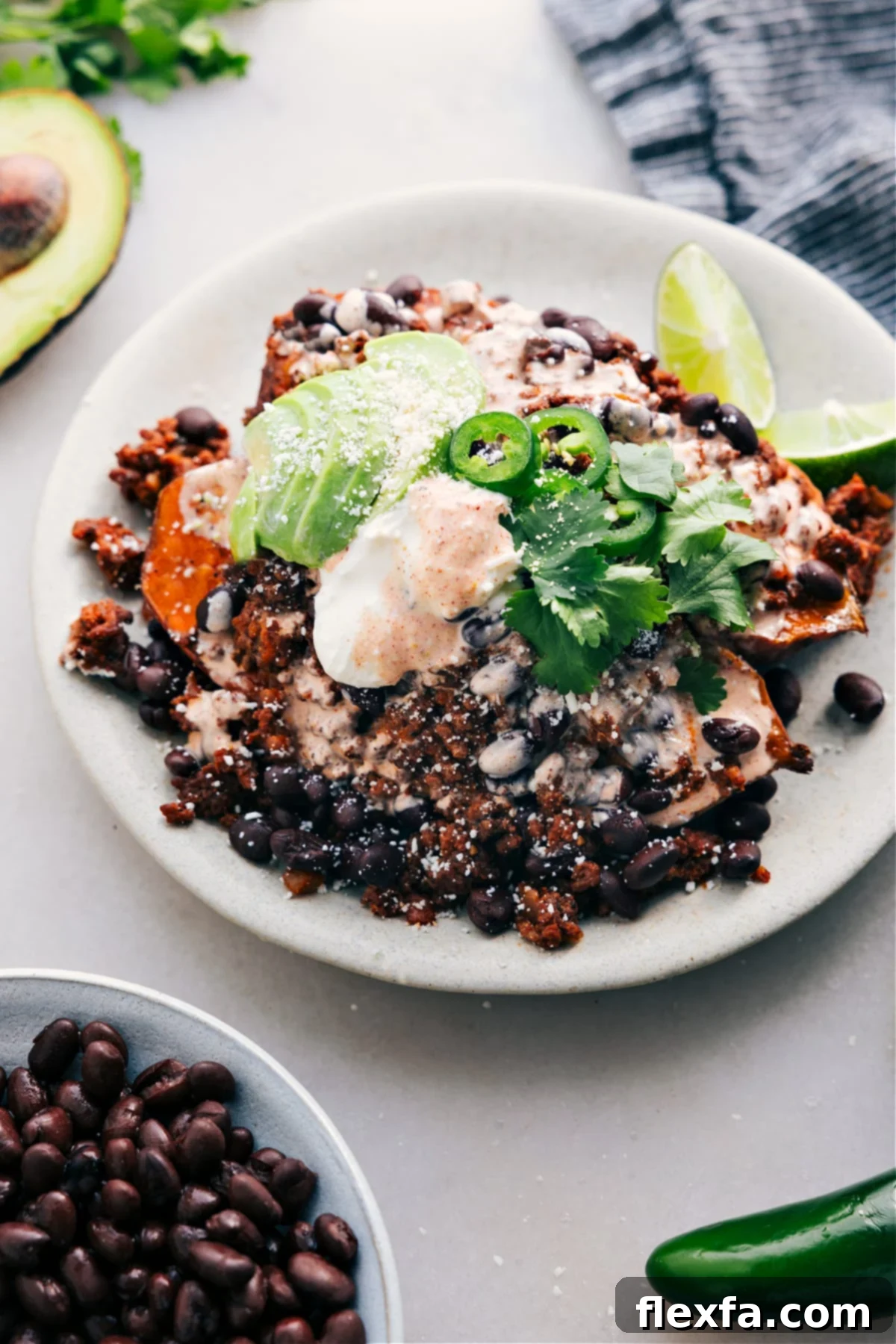 Taco-Stuffed Sweet Potatoes Recipe Taco Stuffed Sweet Potatoes are served on a plate and loaded with meat, avocado, sauce, jalapeño, and fresh cilantro.