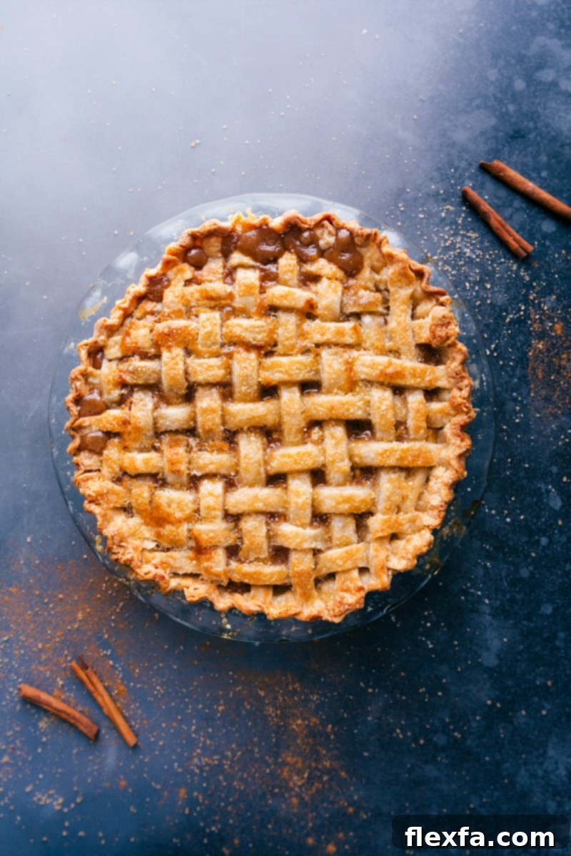 A freshly baked, uncut apple pie, still warm from the oven, showcasing its thick, buttery crust and golden-brown surface.