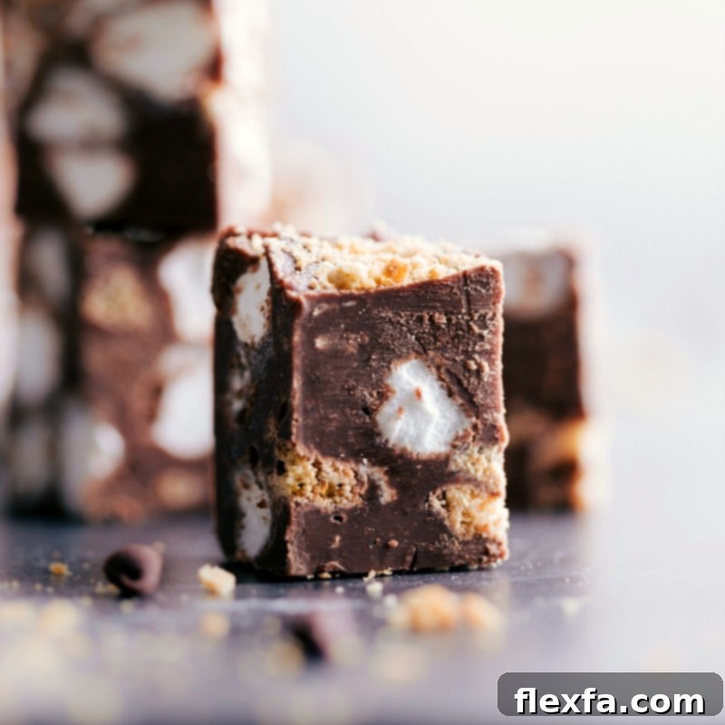A close-up of a delightful piece of Easy Stovetop S'mores Fudge, showcasing its delicious texture and ingredients. Close-up view of a perfectly cut piece of S'mores Fudge, showing the distinct layers of chocolate, graham cracker, and marshmallow texture.