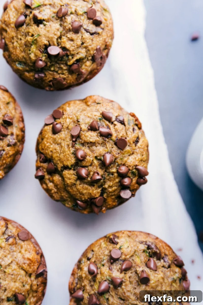 Gluten free zucchini muffins freshly out of the oven, topped with mini chocolate chips, ready to be enjoyed as a delicious breakfast or snack.