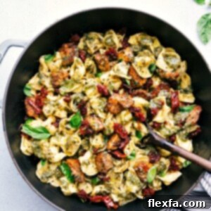 Pesto Chicken Tortellini in a pot, garnished with basil and Parmesan, ready to be served