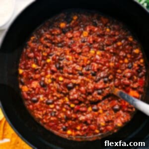 A close-up shot of the savory Turkey Chili in a serving bowl, beautifully garnished with fresh cilantro and a dollop of sour cream, ready to be enjoyed.