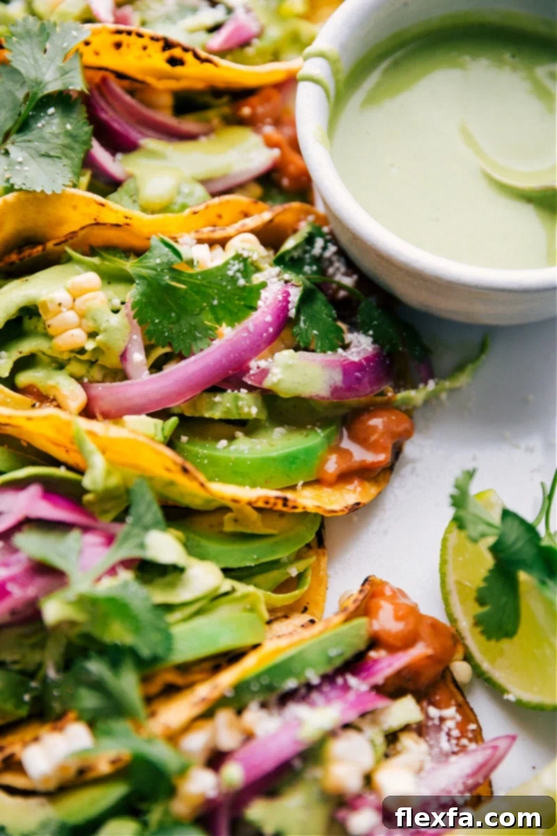 Overhead shot of freshly assembled Pinto Bean Tacos, bursting with colorful toppings including saucy beans, cilantro-lime slaw, crisp corn, and pickled red onions.