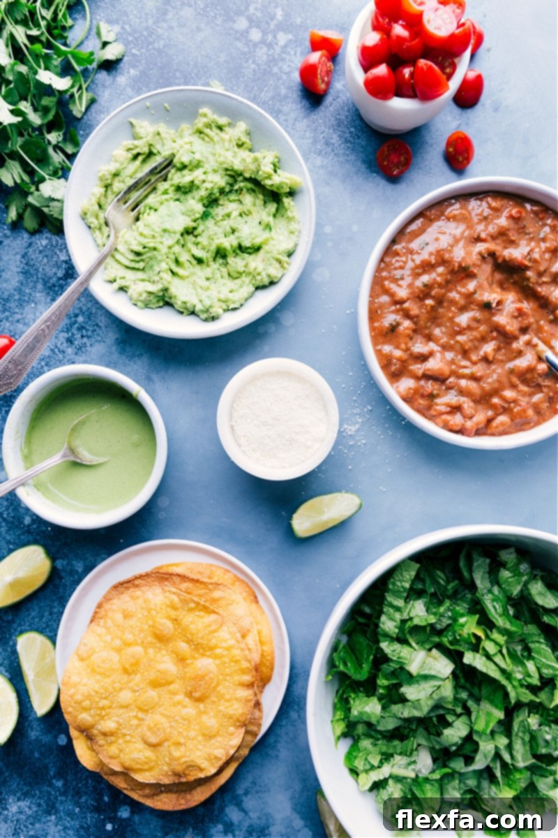 Fresh ingredients for Bean Tostadas: beans, avocado, veggies, and sauce components. A beautiful flat lay image showcasing all the fresh ingredients needed for Bean Tostadas: tortillas, avocado, pinto beans, lettuce, tomatoes, queso fresco, cilantro, and limes.