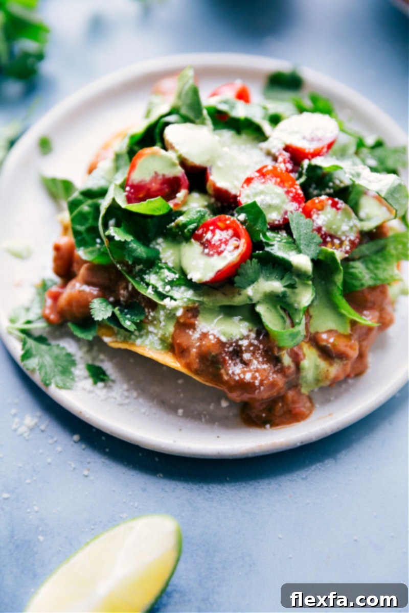 A perfectly assembled, delicious Bean Tostada ready to be enjoyed. Close-up image of a fully assembled and ready-to-eat Bean Tostada, showcasing its vibrant layers of fresh ingredients.