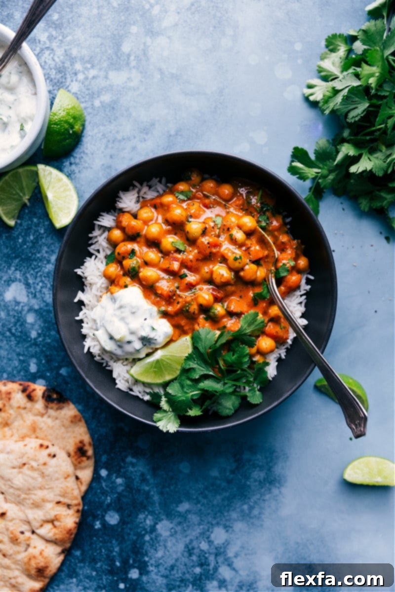 A delicious, flavor-packed Chickpea Curry with aromatic spices, tender chickpeas, and a creamy coconut sauce, perfect for a vegan and gluten-free weeknight meal. Flavor-packed Chickpea Curry, served elegantly with fluffy basmati rice, fresh cilantro, warm naan bread, and a side of cooling coconut raita.