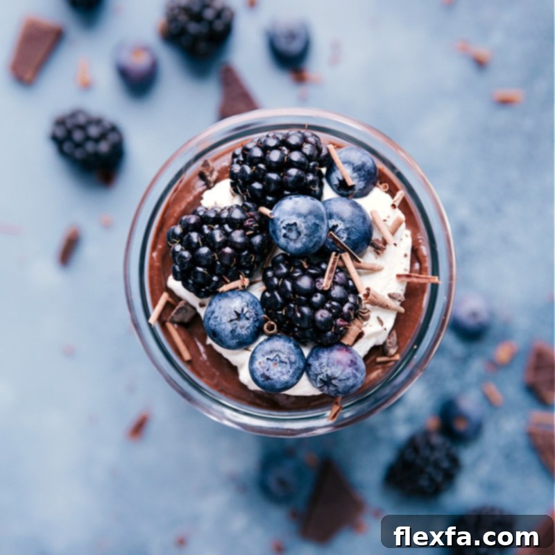 Chocolate Chia Seed Pudding with whipped cream and fresh berries on top, served in a glass jar.