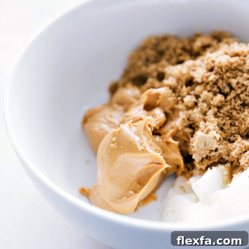 Creamy peanut butter, brown sugar, and solid coconut oil perfectly measured and ready in a mixing bowl.