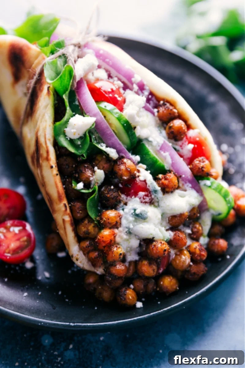Close-up image of two delicious Vegetarian Gyros, showcasing the roasted chickpeas, fresh vegetables, and tzatziki sauce inside warm pita bread.