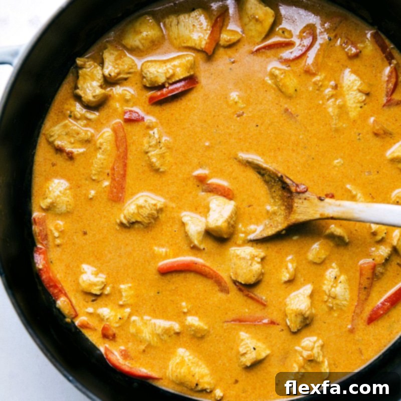 The flavorful chicken curry simmering in a large skillet, rich with sauce and aromatic spices, promising a delicious meal.