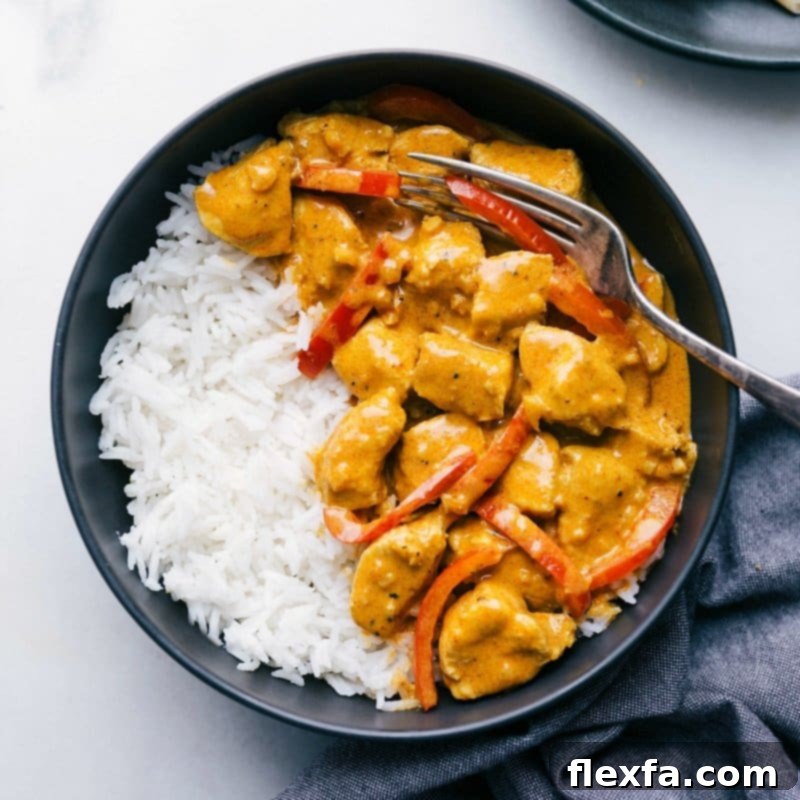 The finished chicken coconut curry expertly plated over a bed of fluffy white rice, garnished with fresh herbs, ready for a delicious meal.