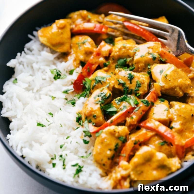 The finished chicken coconut curry served over a bed of white rice, elegantly garnished with fresh cilantro and lime wedges, ready to be savored.