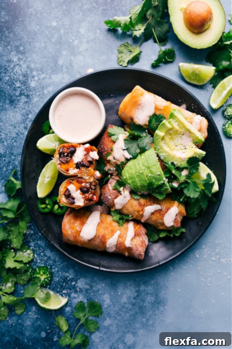 These Air Fryer Sweet Potato and Black Bean Egg Rolls are loaded with flavor and texture — tender sweet potatoes, savory black beans, and other taco-spiced veggies. Dip or drizzle a spiced chili-lime sauce over these egg rolls and be prepared for a new dinner addiction! Recipe via chelseasmessyapron #dinner #lunch #quick #easy #vegetarian #best #sauce #healthier #airfryer #blackbean #eggrolls Crispy Air Fryer Sweet Potato and Black Bean Egg Rolls served on a plate with a side of chili-lime sauce, garnished with fresh cilantro.