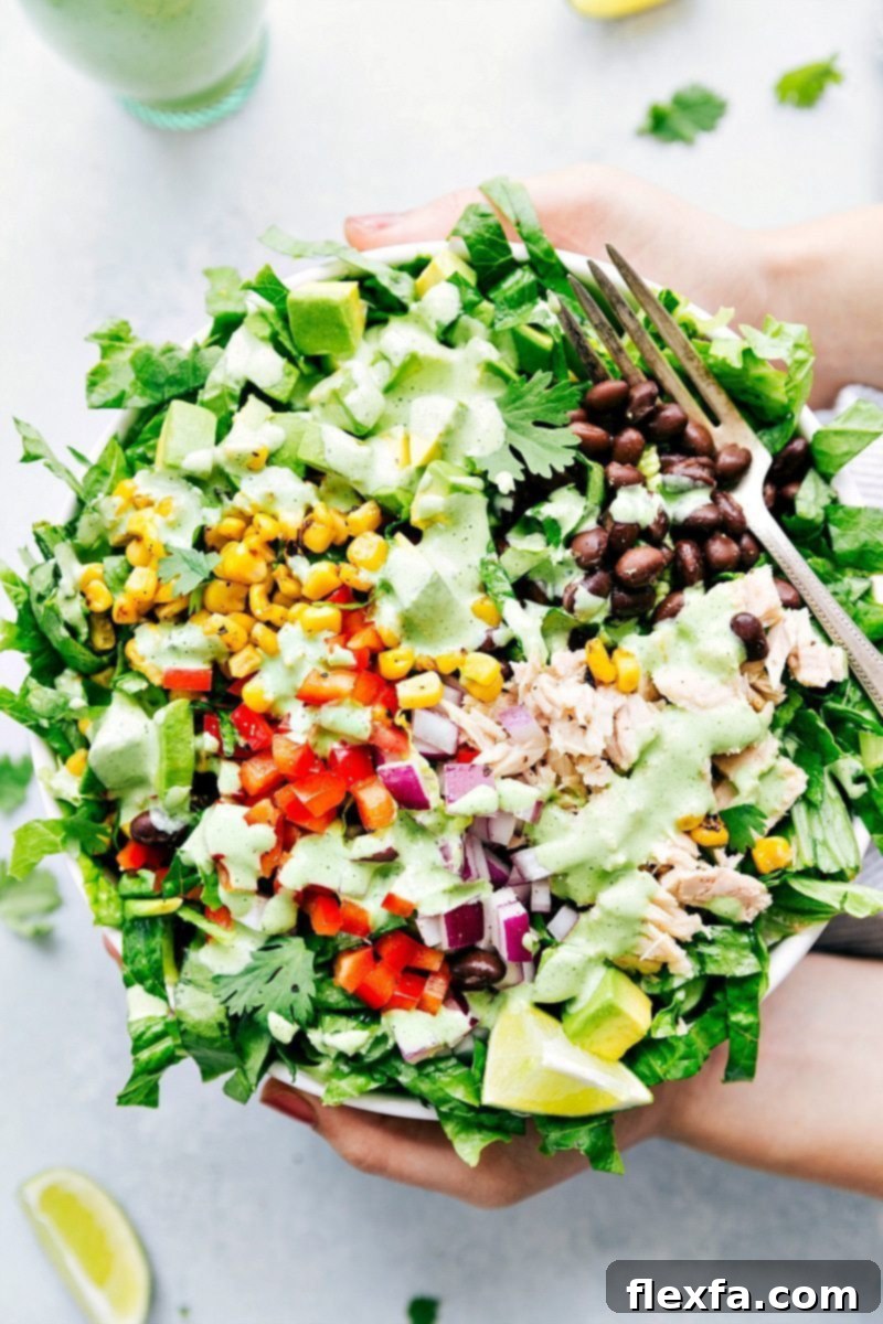 Overhead shot of a vibrant, fresh salad generously drizzled with the homemade creamy Cafe Rio Dressing, highlighting its appealing texture and color against crisp greens and other toppings.