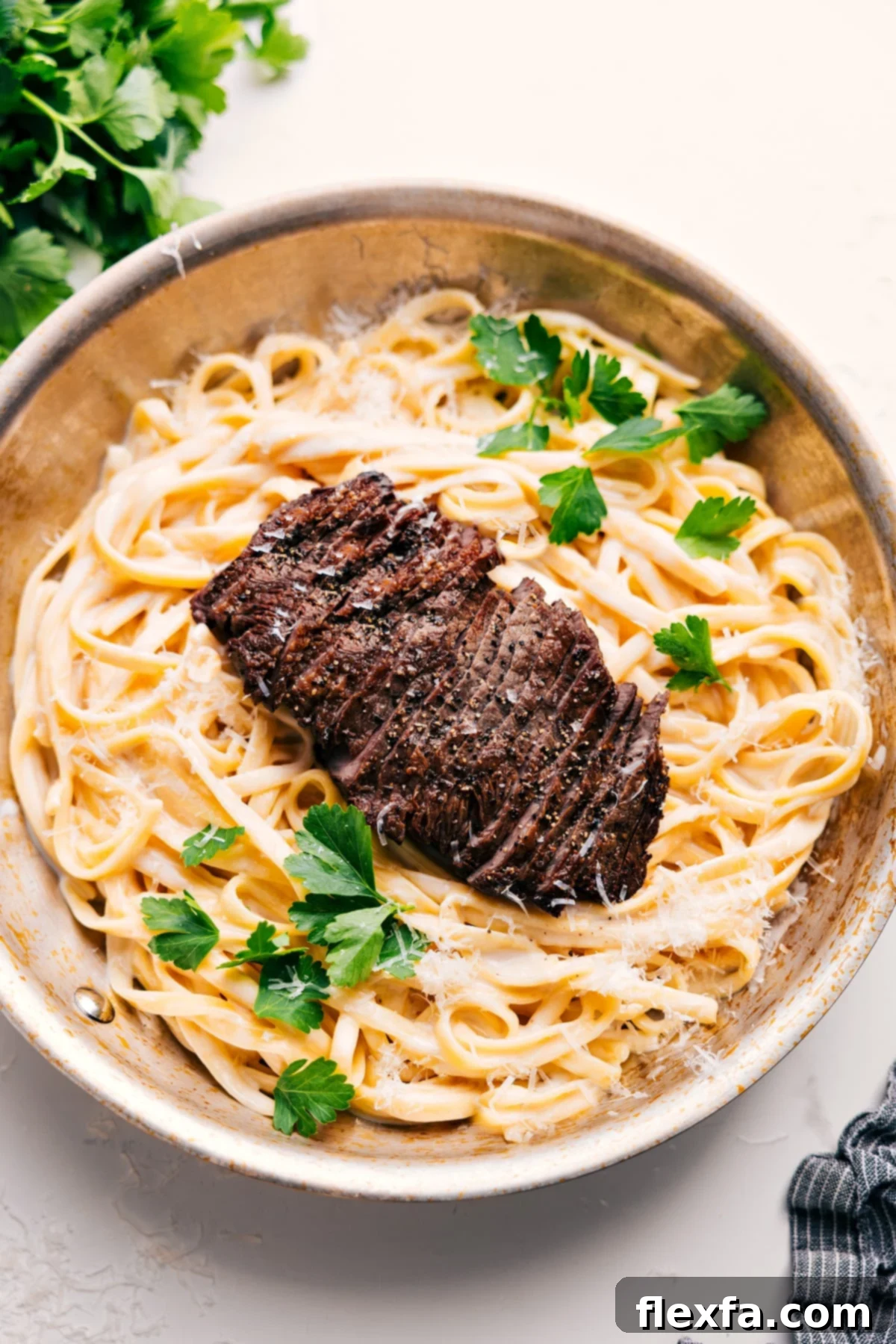 Steak Alfredo Recipe plated and garnished with fresh parsley.