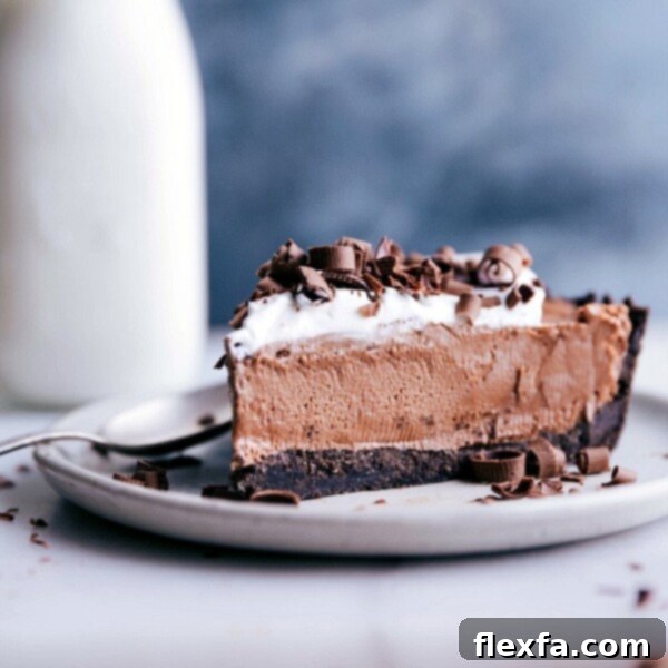 A decadent slice of nutella pie, crowned with whipped cream and chocolate shavings, on a plate with a spoon, inviting a bite.