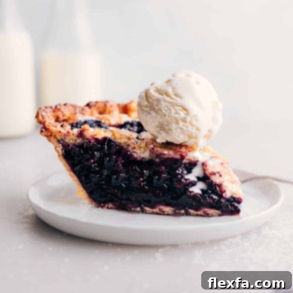 Slice of berry pie with ice cream on top.