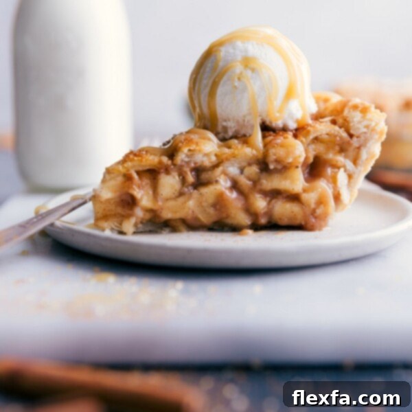 Slice of apple pie with ice cream and caramel sauce on top.