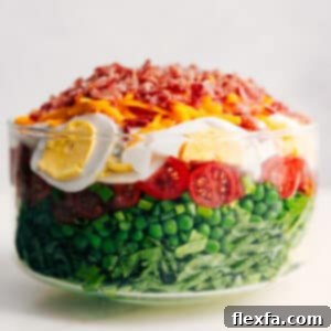 A vibrant and fresh 7 Layer Salad in a glass bowl, showcasing its distinct, colorful layers, ready to be served.