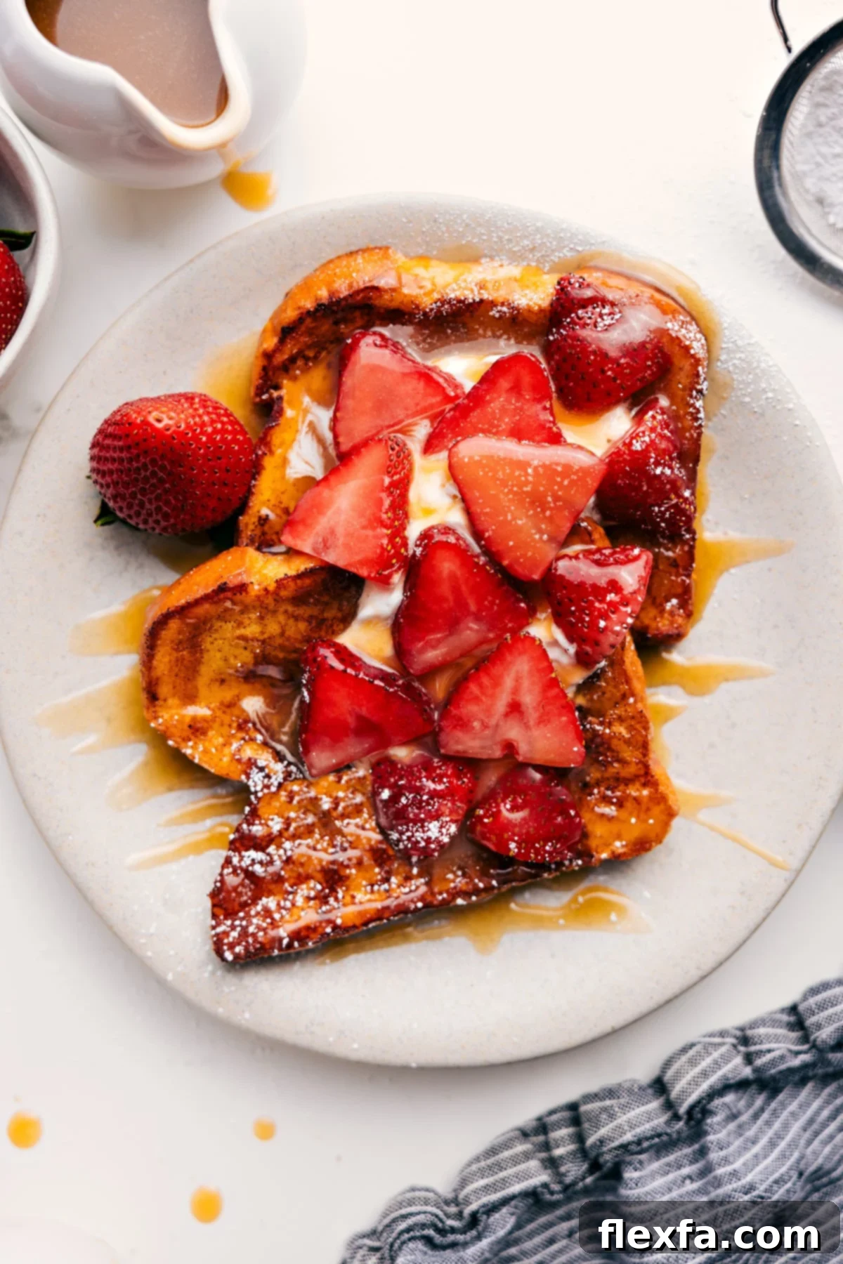 Exquisite French Toast Recipe served on a white plate, generously topped with fluffy fresh whipped cream, vibrant sliced strawberries, and a luscious drizzle of homemade caramel syrup.