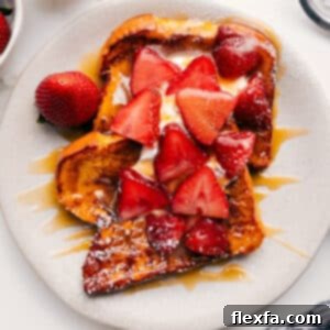 A perfectly golden stack of French Toast topped with whipped cream and berries