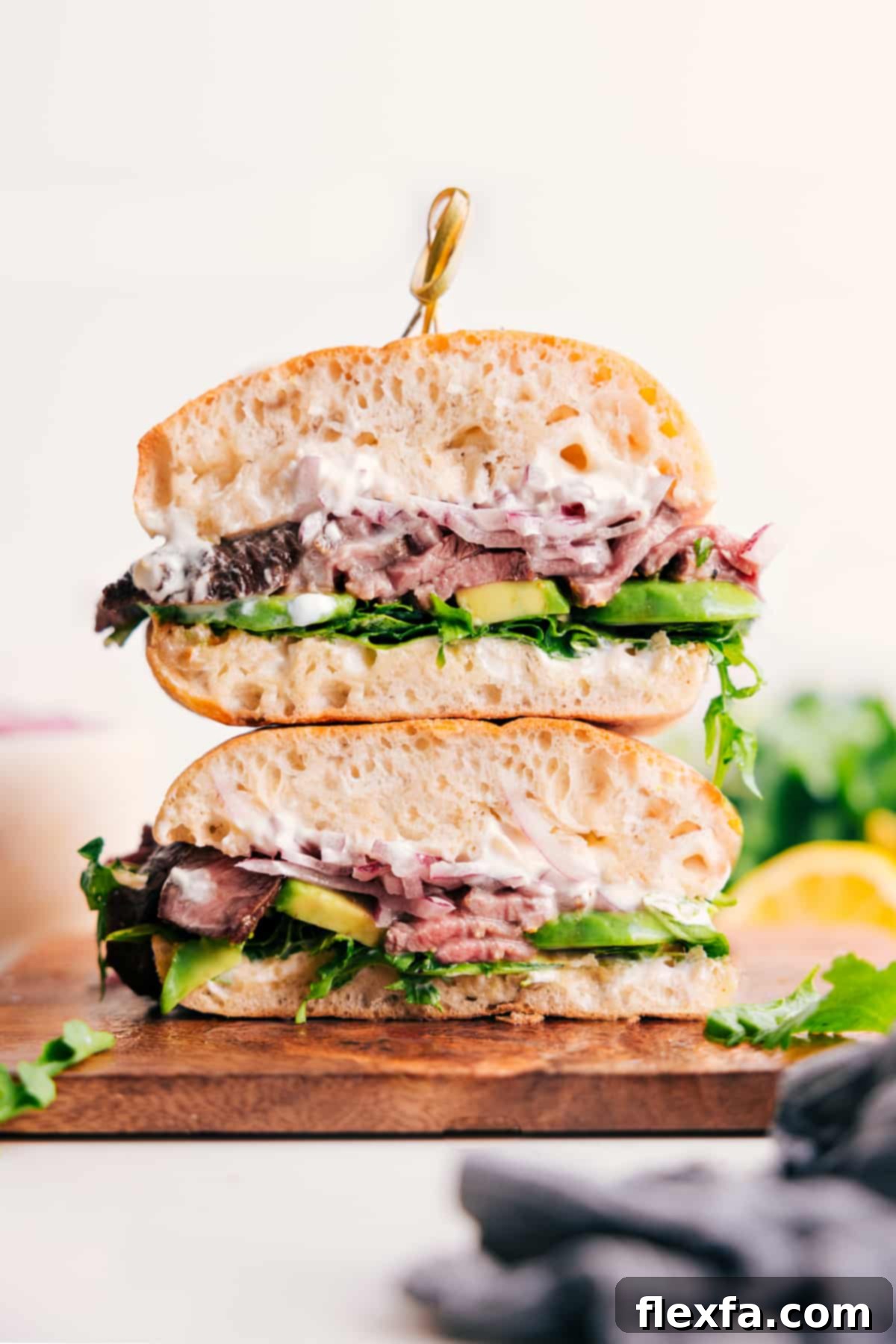 The Ultimate Steak Sandwich layered with steak, avocado, and pickled onions.