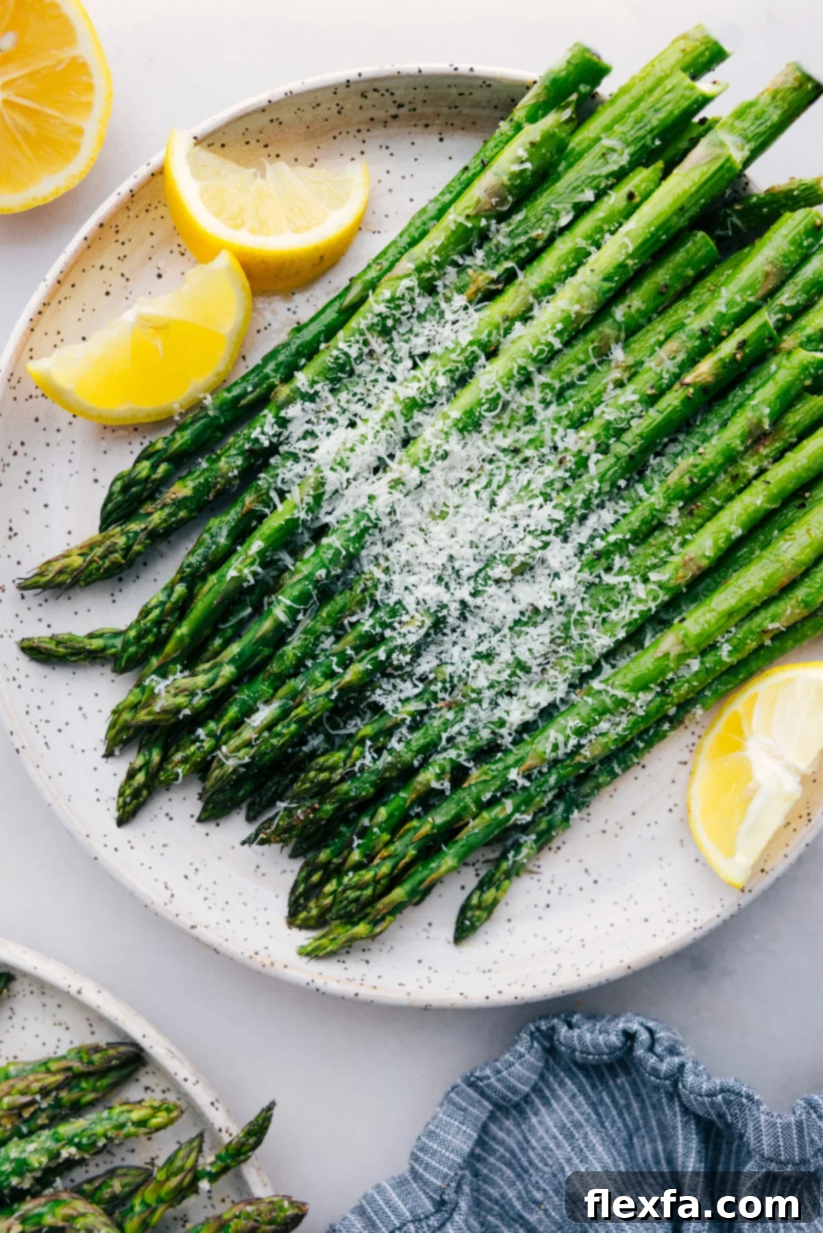 Deliciously roasted asparagus spears garnished with fresh Parmesan and lemon slices.