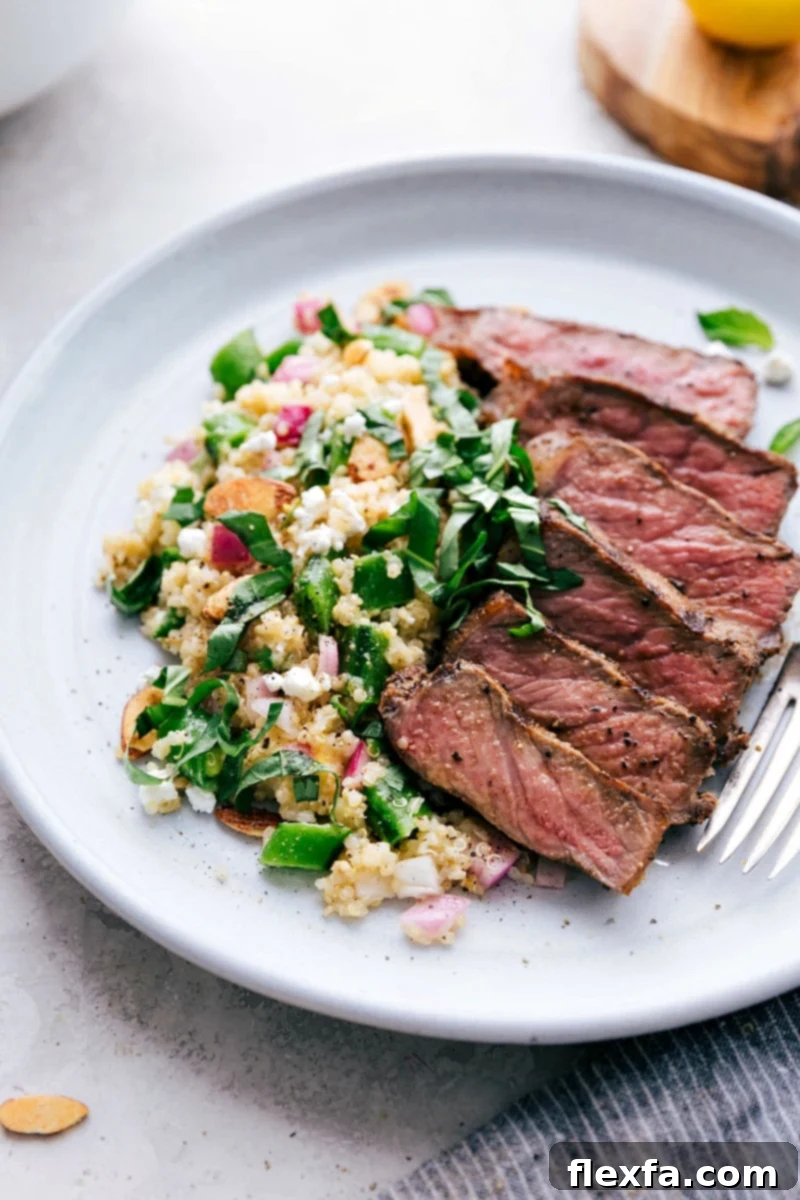 A vibrant Spring Quinoa Salad with grilled steak, garnished with fresh herbs.