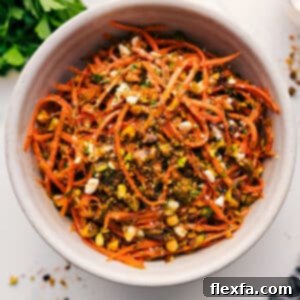 A colorful and delicious Ribbon Carrot Salad in a serving bowl, garnished with fresh herbs and pistachios.