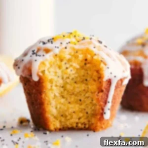 Lemon poppy seed muffin with a fresh bite mark, revealing its moist interior, and adorned with creamy frosting.