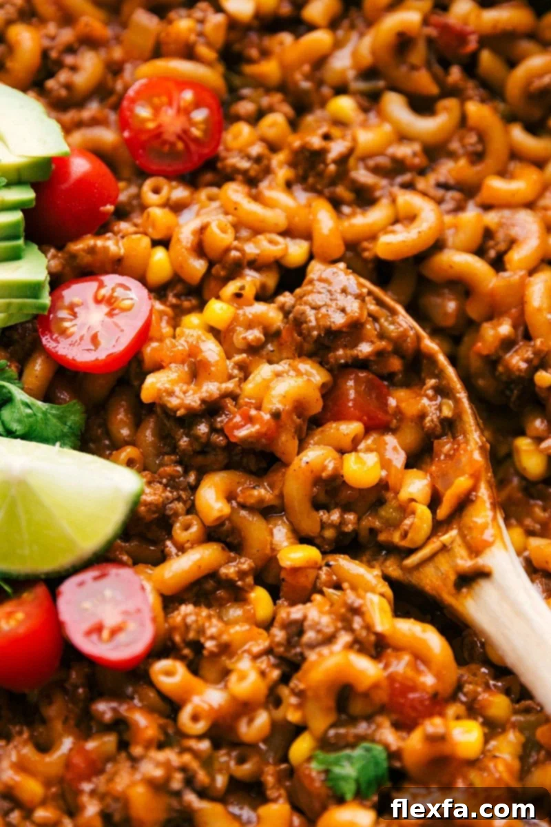 A spoonful of cheesy Taco Pasta, showcasing seasoned ground beef, tender pasta, sweet corn, and melted cheese, fresh from the pan.