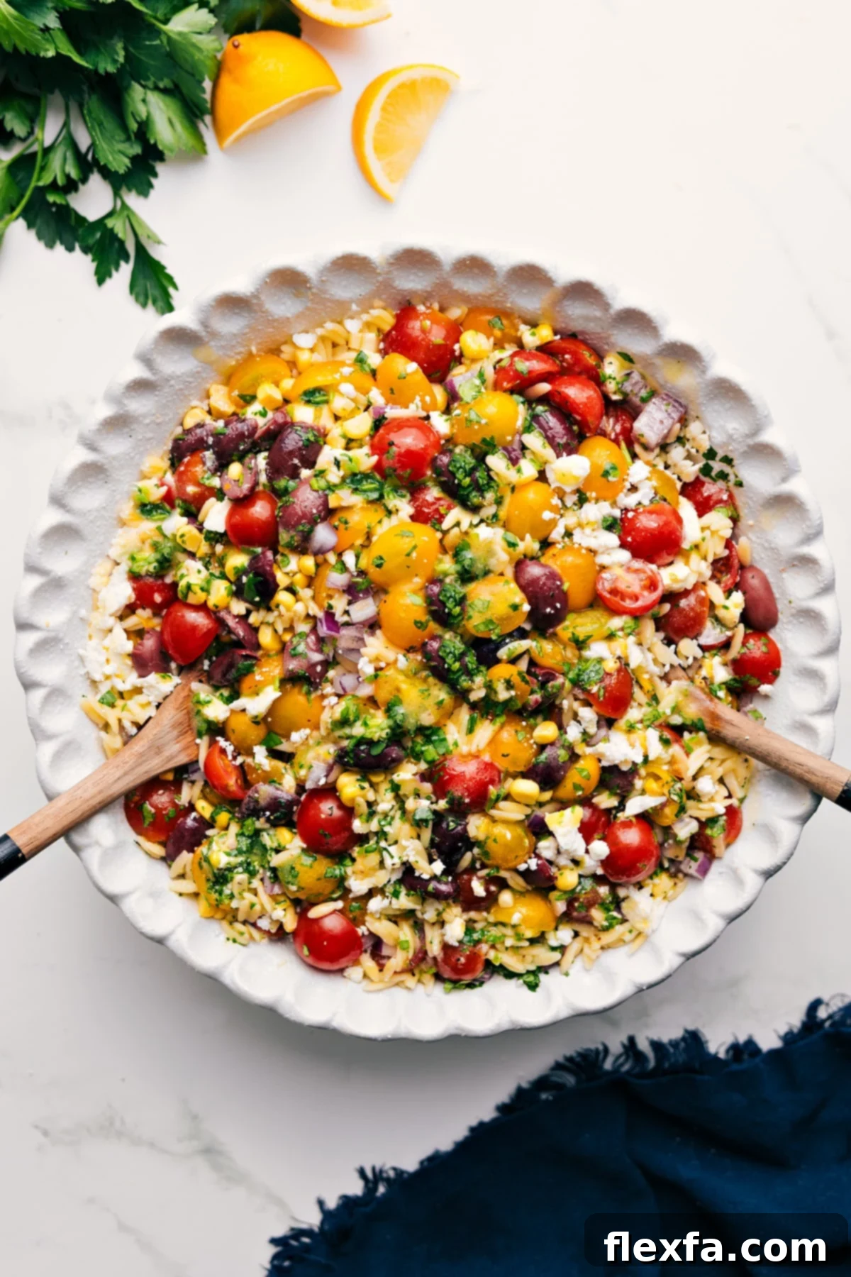 A vibrant Greek Orzo Pasta Salad, brimming with tender orzo, juicy tomatoes, olives, sweet corn, fresh herbs, and feta in a lemon dressing.