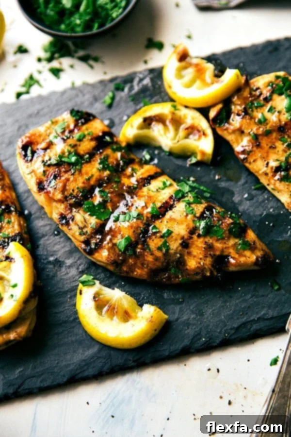 The best grilled chicken marinade recipe, garnished with fresh herbs and lemon wedges, ready for a BBQ.
