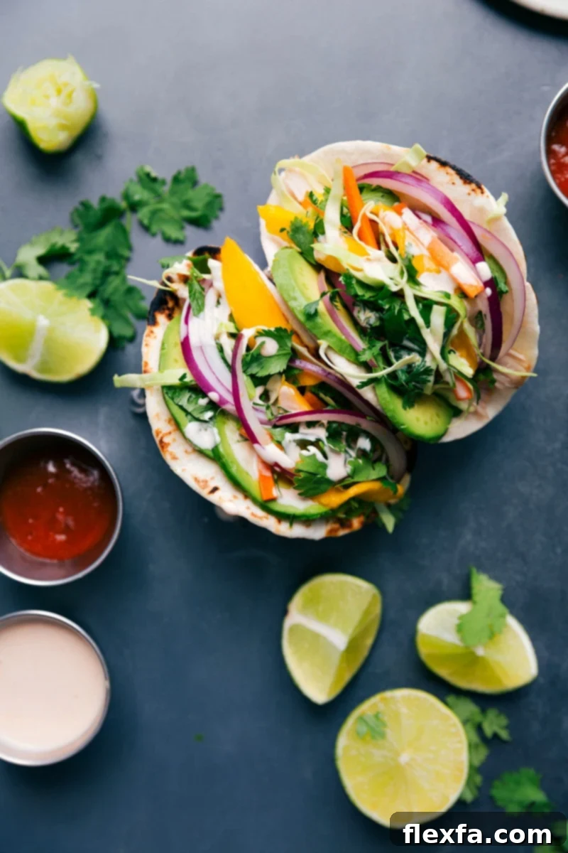 Colorful Asian chicken tacos, filled with chicken, mango slaw, creamy avocado, and a sriracha-lime sauce.