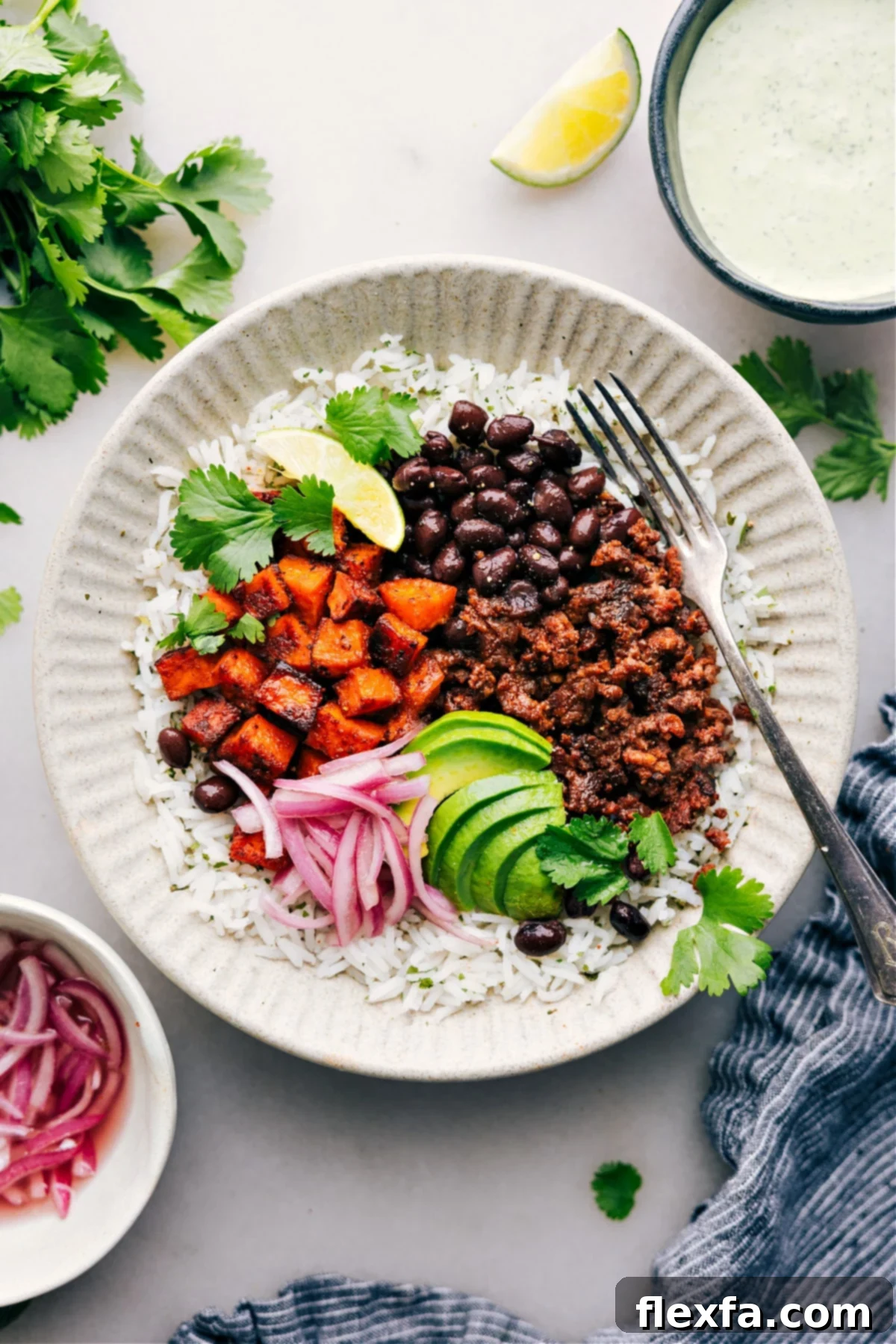 Healthy ground beef recipes: A hearty beef burrito bowl featuring pickled red onions, roasted sweet potatoes, and a creamy cilantro-lime sauce.