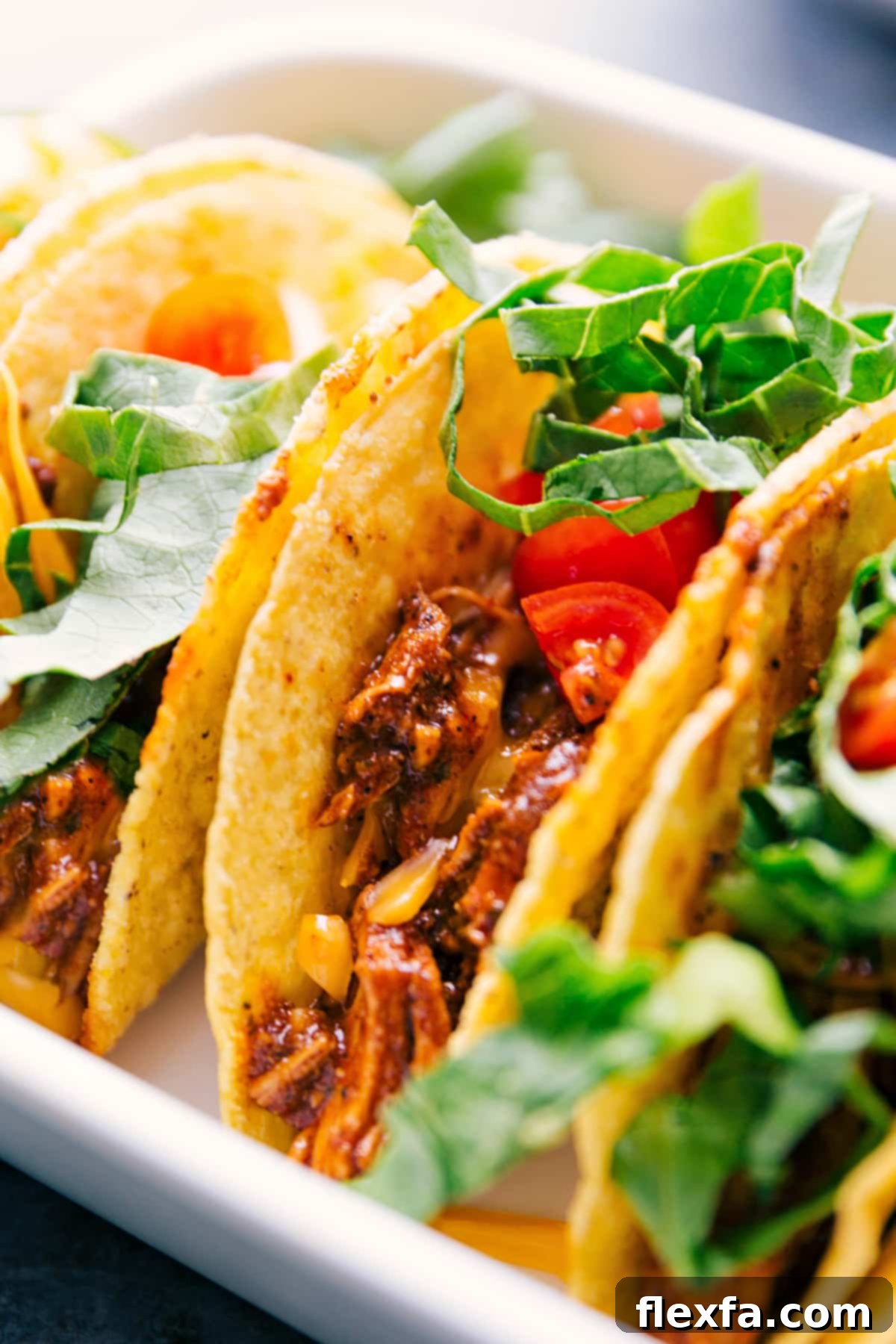 Delicious rotisserie chicken tacos in a pan, garnished with fresh lettuce and diced tomatoes, ready to serve.