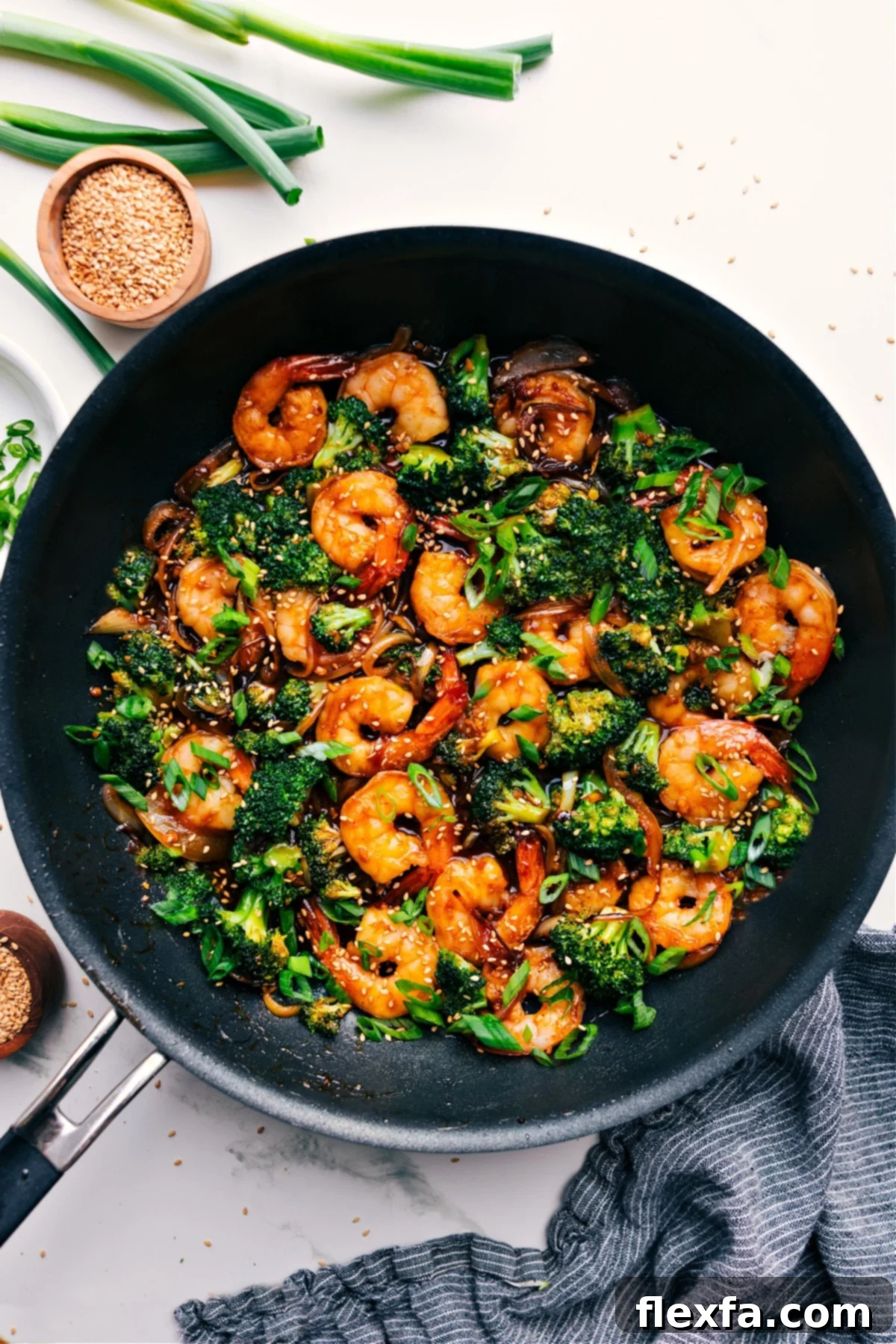 Succulent honey garlic shrimp simmering in a pot, generously topped with sesame seeds.