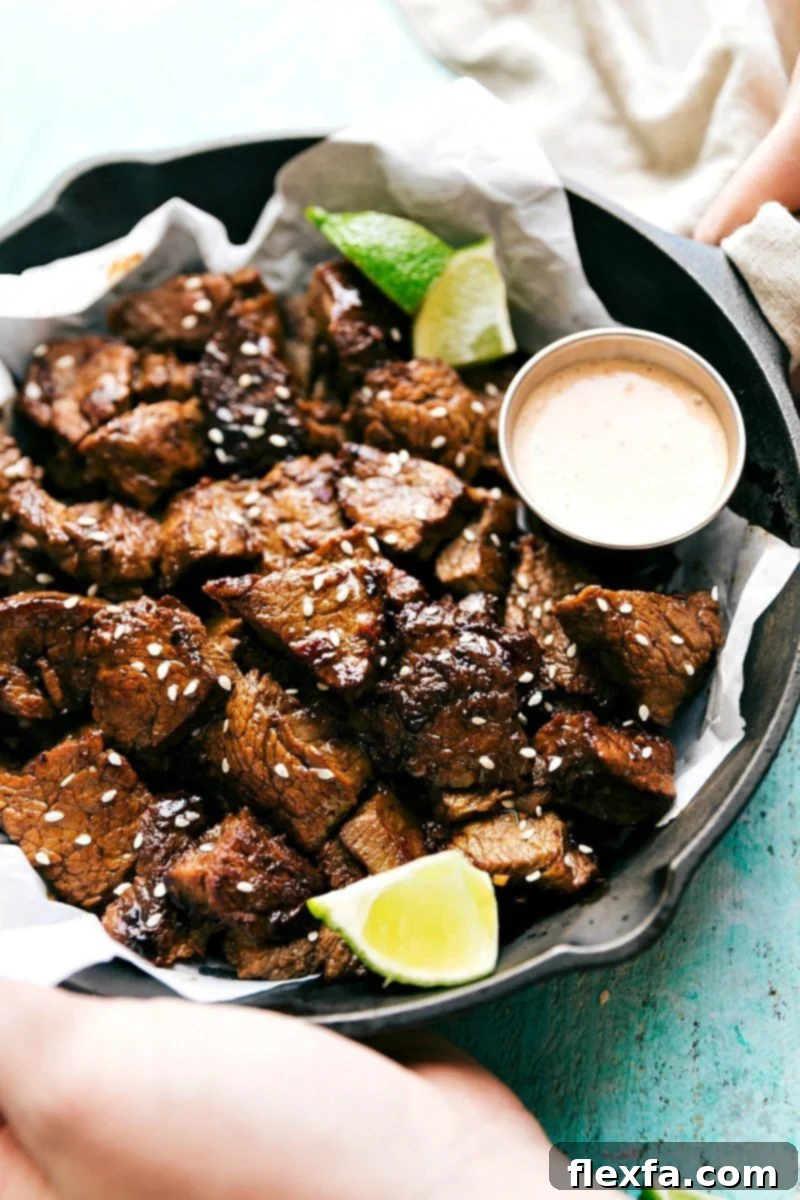 Tender and flavorful Asian steak bites arranged next to a small bowl of dipping sauce.