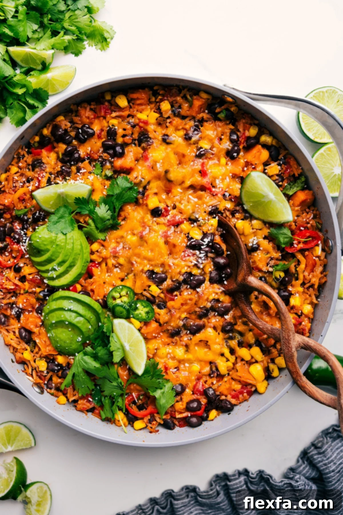 A colorful one-pot burrito bowl, generously topped with fresh cilantro, lime wedges, creamy avocado, and spicy jalapeños.
