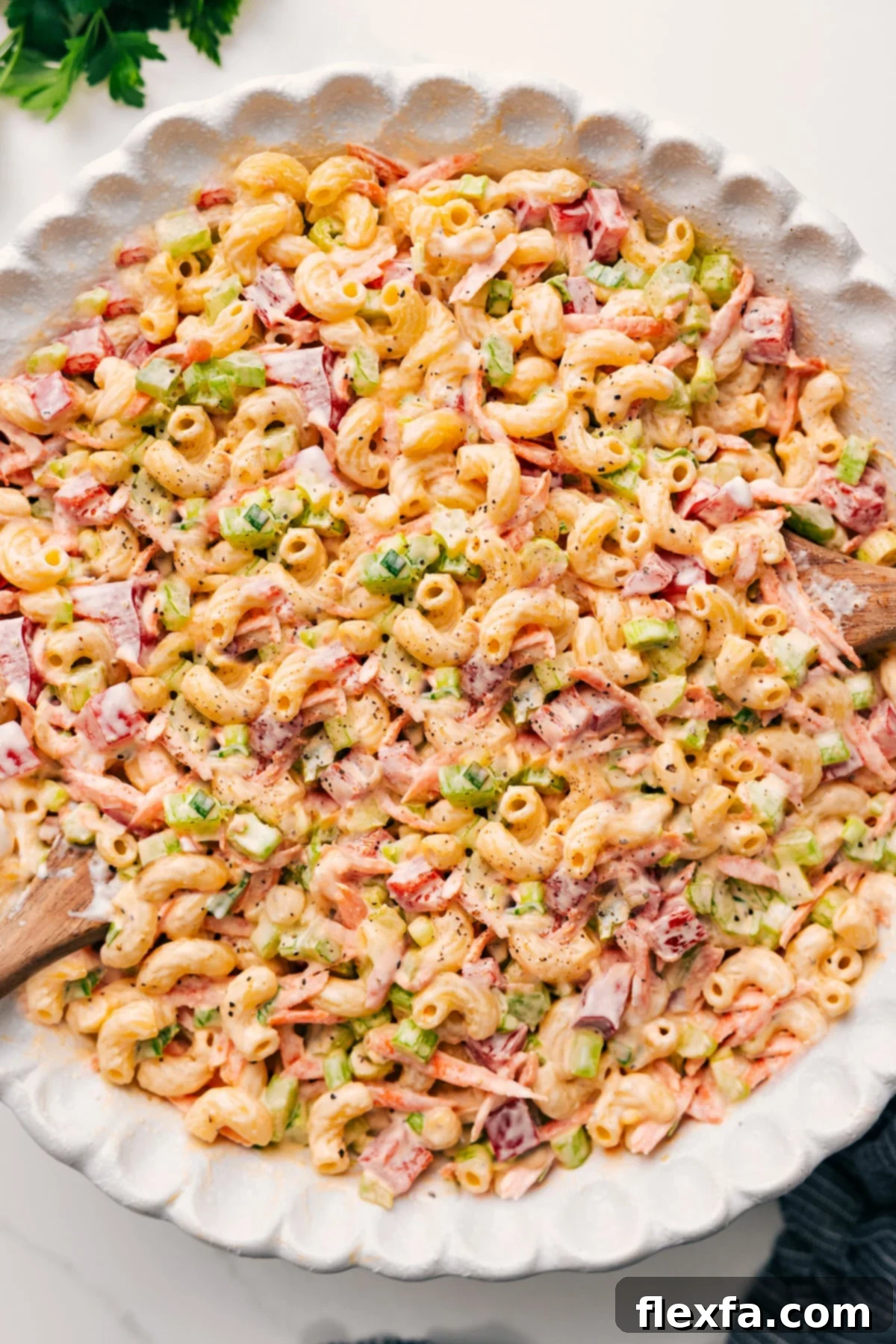 A large bowl of creamy macaroni salad, perfectly tossed with colorful vegetables and ready to be served. The texture appears inviting and vibrant.
