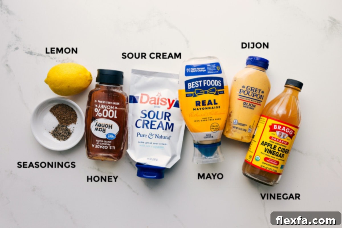 All the distinct ingredients for the easy coleslaw recipe dressing, including fresh lemon, various spices, golden honey, creamy sour cream, rich mayonnaise, and tangy Dijon mustard, meticulously arranged and ready for mixing.