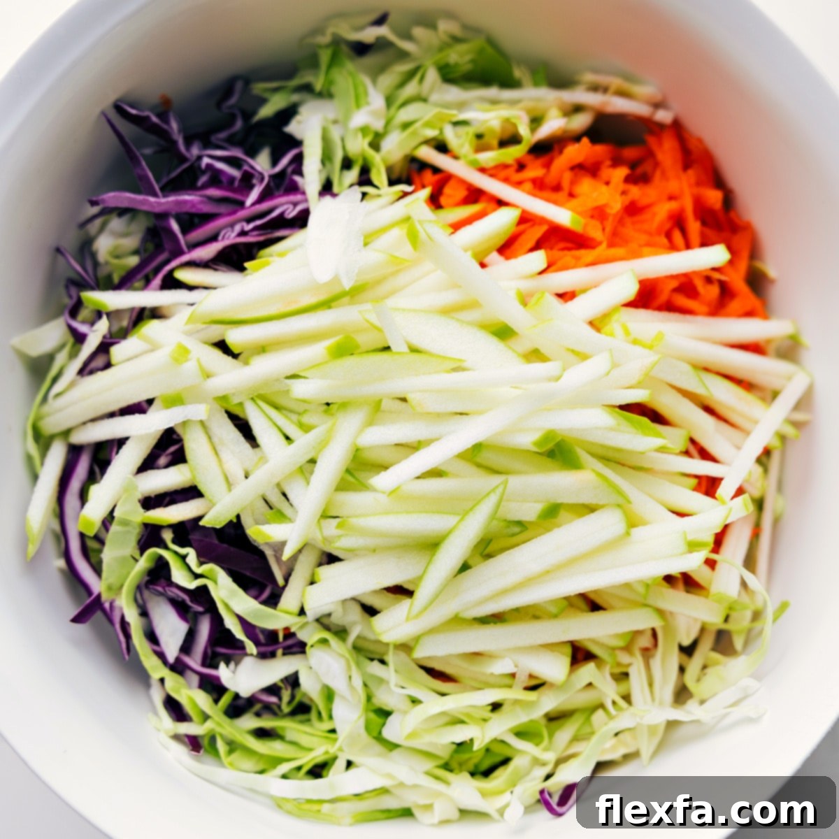 Base ingredients for the Easy Coleslaw Recipe (sliced green and red cabbage and shredded carrots) added to a large mixing bowl, patiently waiting for the rich, creamy dressing.