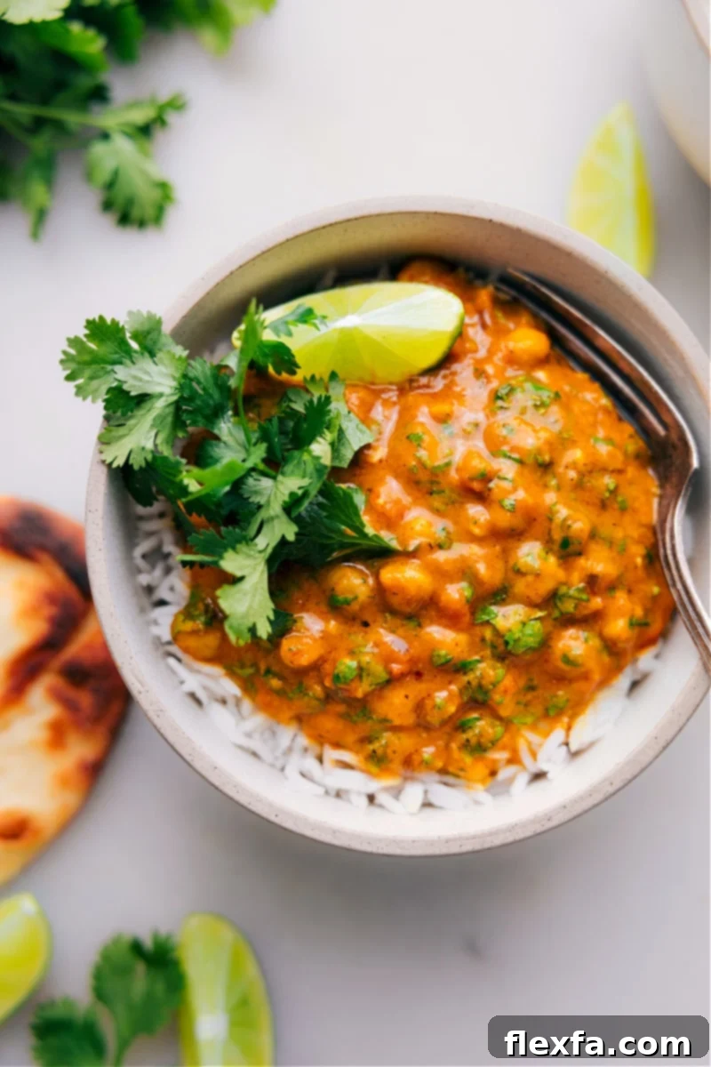 A cozy bowl of creamy pumpkin curry with chickpeas, garnished with fresh cilantro and a lime wedge, perfect for autumn.