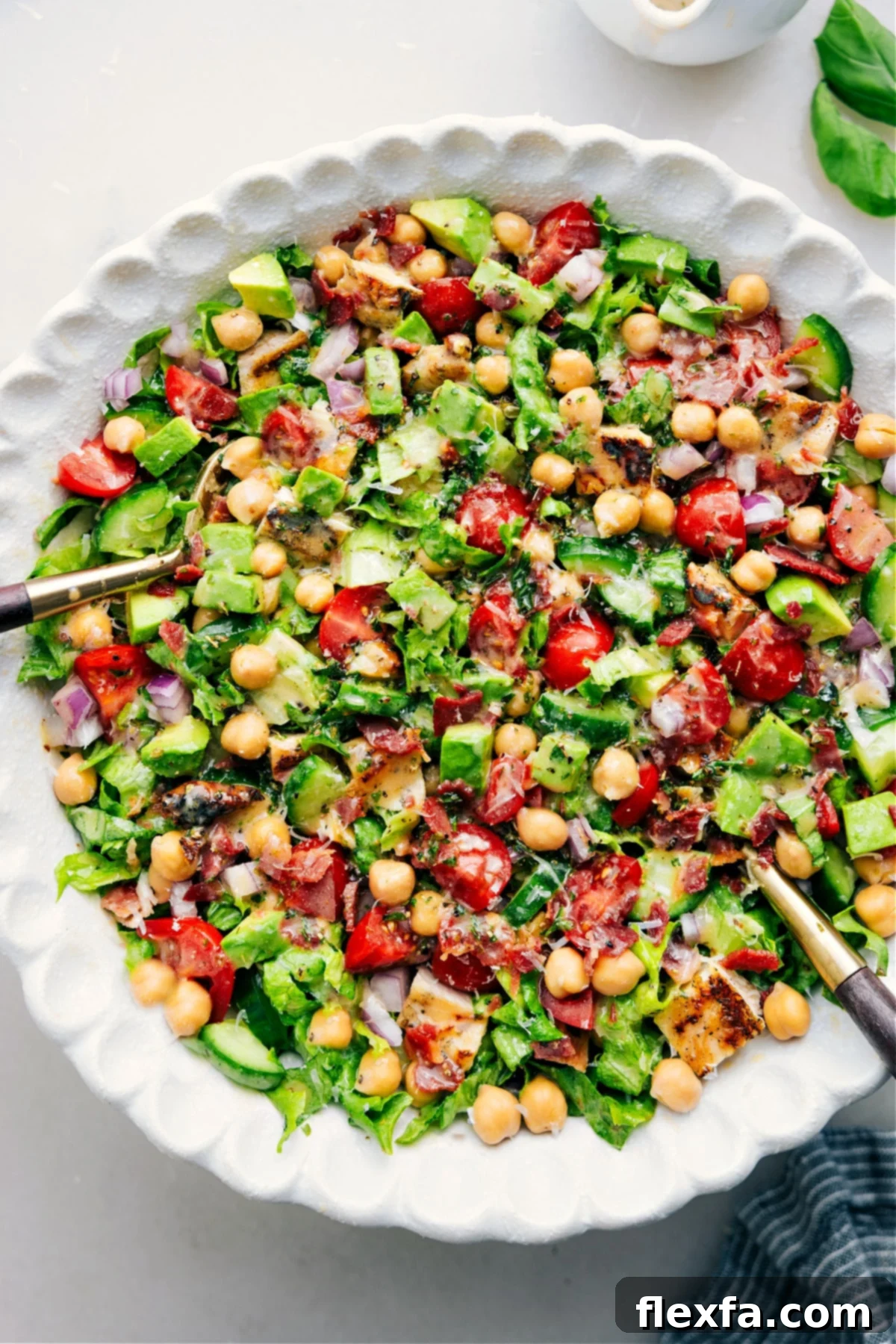 A colorful chopped chicken salad in a bowl, thoroughly tossed with dressing, offering a fresh and hearty meal.