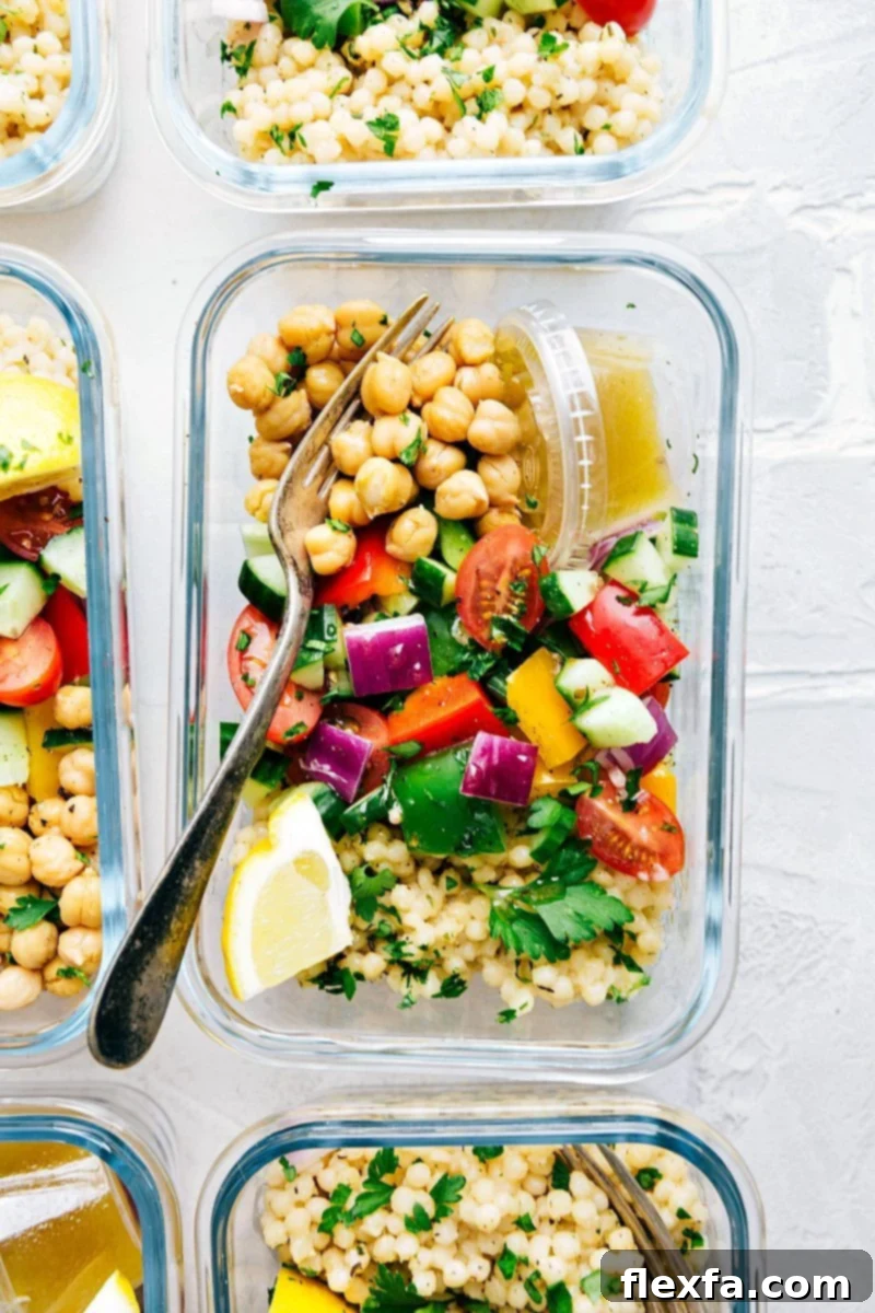 Colorful Greek couscous salad arranged in meal prep containers, ready for healthy and convenient meals.