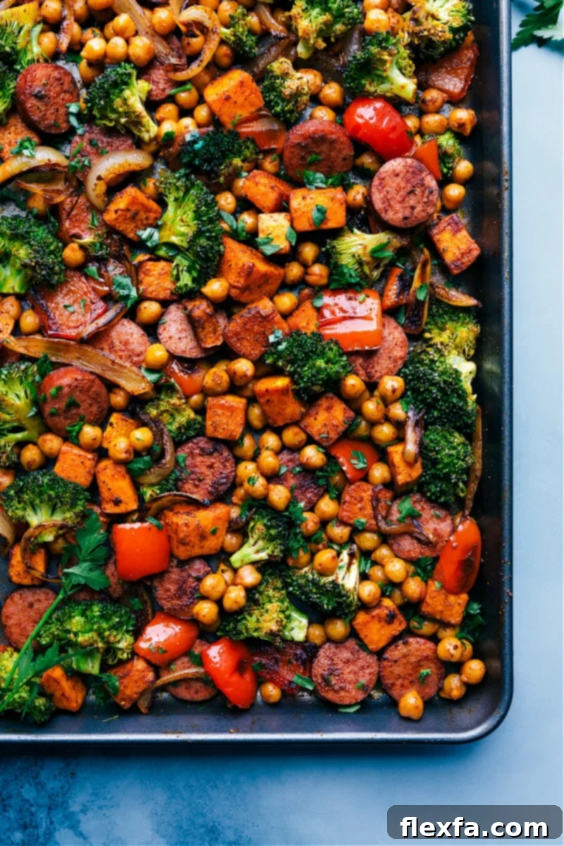 A sheet pan filled with savory one-pan sausage and chickpeas, mixed with vibrant vegetables and Mexican-inspired seasoning.
