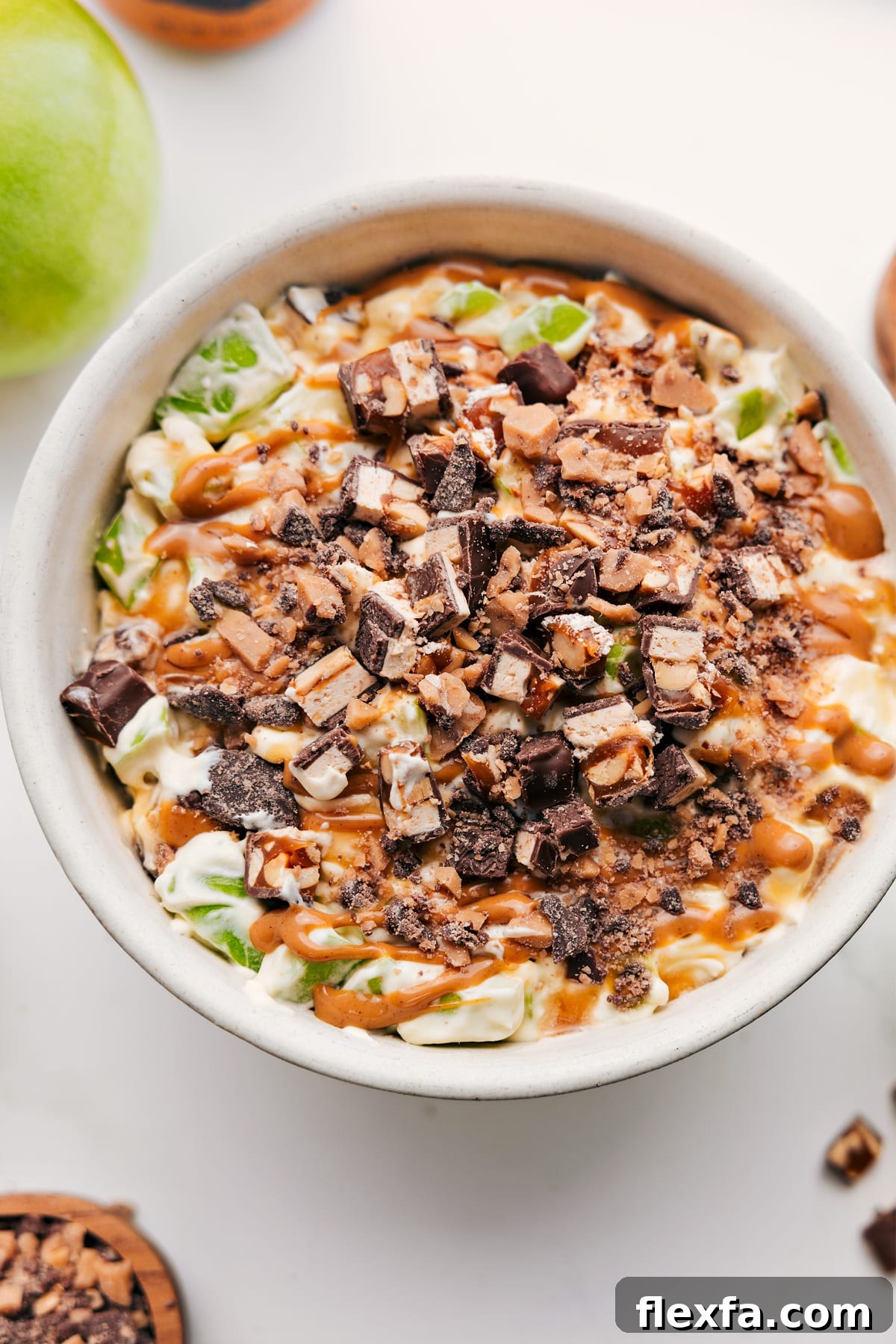 Snickers Salad Recipe in a bowl topped with chopped Snickers and a drizzle of caramel sauce