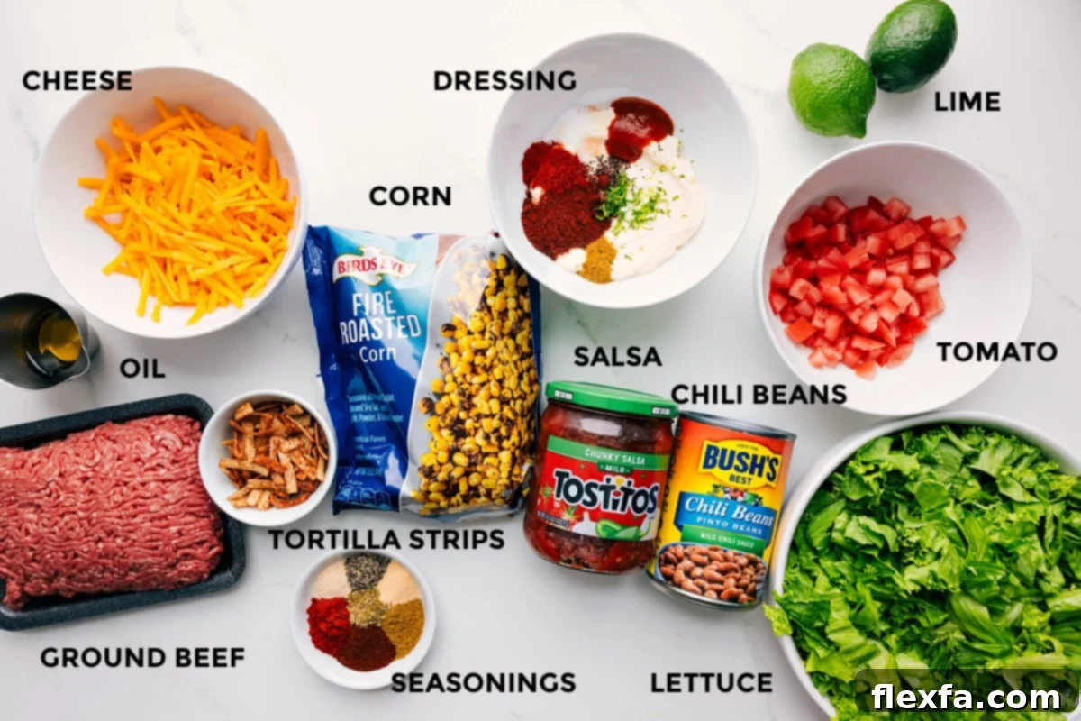 A display of all the fresh ingredients needed for this easy taco salad recipe, including ground beef, spices, cheese, lettuce, tomatoes, and dressing components.
